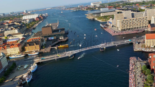 Video - Copenhagen, Denmark - August 6, 2025: Aerial drone view of the Royal Danish Playhouse on Copenhagen's waterfront, with people walking and cycling across Inderhavnsbroen bridge