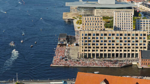 Video - Aerial drone view of the busy Islands Brygge waterfront filled with swimmers, sunbathers, and cyclists in Copenhagen, Denmark