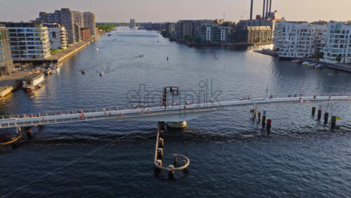 Video - Aerial drone view of the Lille Langebro pedestrian bridge with people cycling and walking across the harbour at sunset in Copenhagen, Denmark