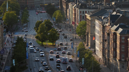 Video - Copenhagen, Denmark - August 6, 2025: Aerial drone view of evening city traffic flowing along a wide street lined with historic brick buildings in Norre Voldgade