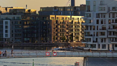 Video - Copenhagen, Denmark - August 6, 2025: Aerial drone view of people cycling and walking across the Lille Langebro bridge with modern apartments in the background
