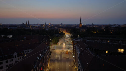 Video - Aerial drone view of the city with car lights glowing along H.C. Andersens Boulevard and church towers in the distance in the evening in Copenhagen, Denmark