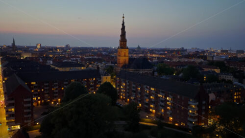 Video - Aerial drone view of the skyline with the famous spiral spire of the Church of Our Saviour lit against the evening sky in Copenhagen, Denmark
