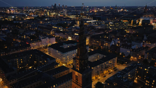 Video - Aerial drone view of the skyline with the famous spiral spire of the Church of Our Saviour lit against the evening sky in Copenhagen, Denmark