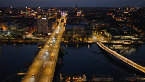 Video - Copenhagen, Denmark - August 6, 2025: Aerial drone view of Amager and Christianshavn at night, with glowing streets, Our Saviour's Church tower, and the harbor in the distance
