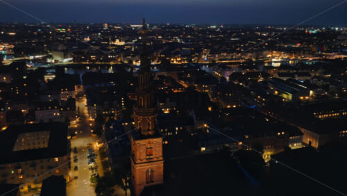 Video - Aerial drone view of the skyline with the famous spiral spire of the Church of Our Saviour lit against the evening sky in Copenhagen, Denmark
