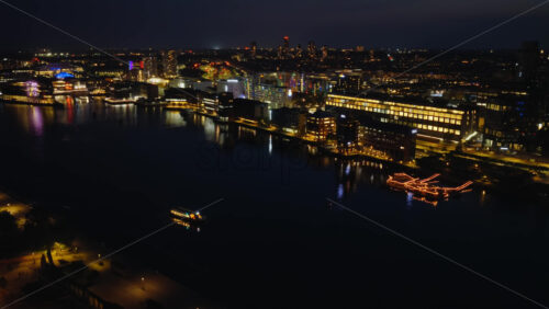 Video - Aerial drone view of Copenhagen Harbor at night with reflections of colorful lights from modern buildings in Denmark
