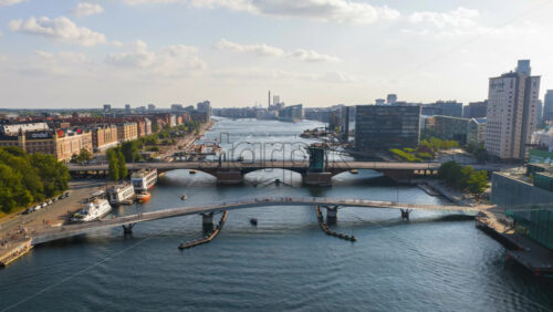 Video - Copenhagen, Denmark - August 8, 2025: Aerial drone time lapse of the Copenhagen harbor bridges with boats crossing and people walking along the waterfront on a sunny day