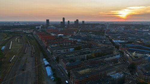 Video - Aerial drone time lapse over Copenhagen rooftops and waterfront with sun rays breaking through the clouds at sunset