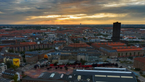Video - Copenhagen, Denmark - August 8, 2025: Aerial drone time lapse over Copenhagen rooftops and waterfront with sun rays breaking through the clouds at sunset