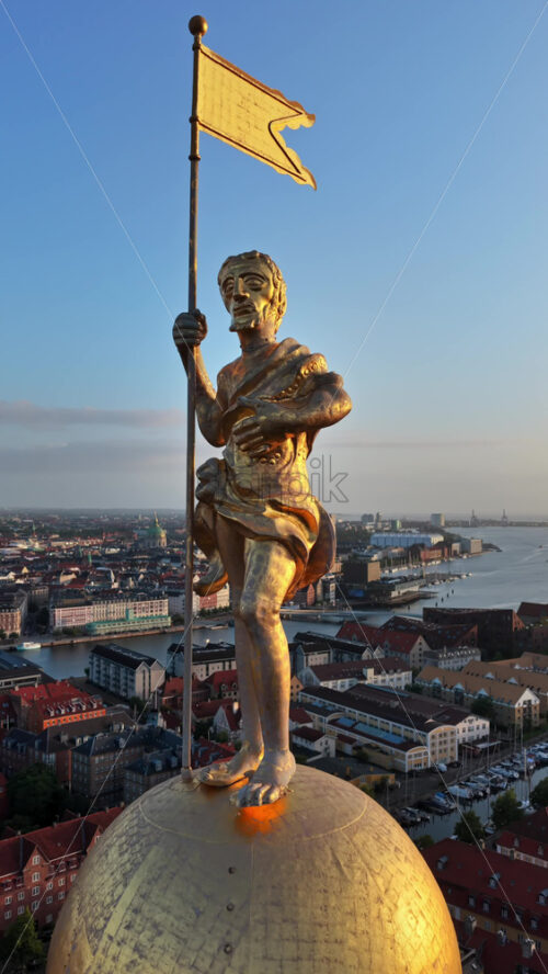 Video - Aerial drone view of the golden statue atop a sphere on the Church of Our Saviour overlooking the Copenhagen skyline, with Frederik's Church dome in the background in Denmark. Vertical