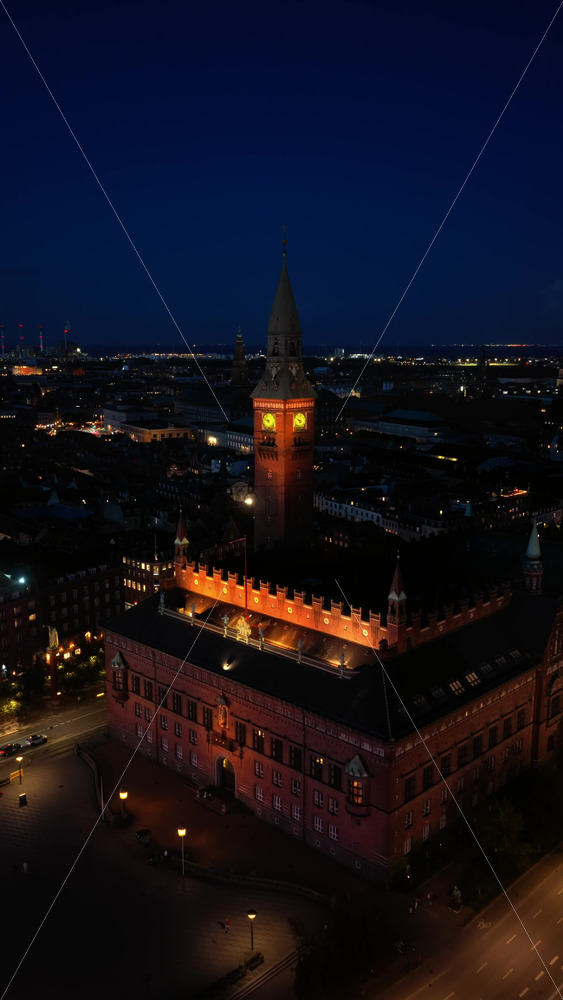 Video - Aerial drone view of Radhuspladsen with Copenhagen City Hall and Tivoli Gardens nearby at night. Vertical