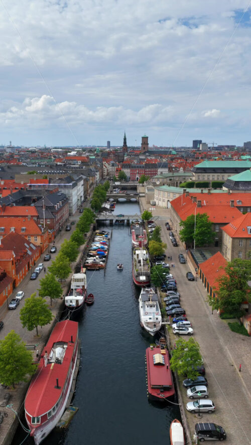 Video - Aerial drone view over the historic Christianshavn Canal lined with colorful houses and moored boats in Copenhagen, Denmark. Vertical
