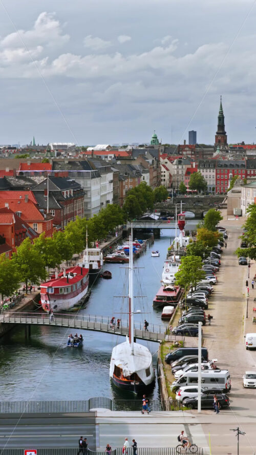 Video - Aerial drone view of the colourful rooftops and canals of Copenhagen, with the Copenhagen City Hall tower standing prominently in the distance. Vertical