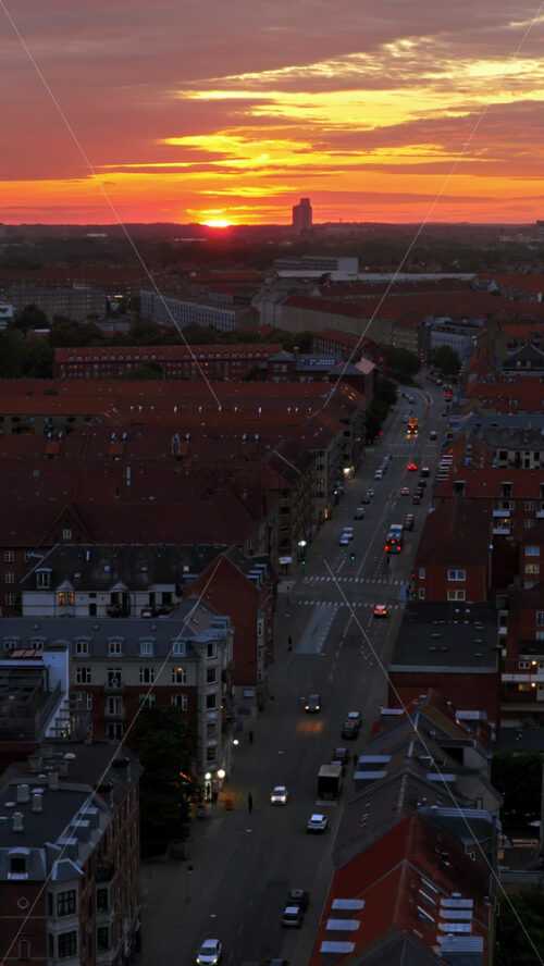 Video - Aerial drone view of of Norrebro rooftops and streets during sunset, with dramatic golden sky over Copenhagen, Denmark. Vertical