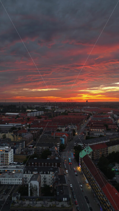 Video - Aerial drone view of of Norrebro rooftops and streets during sunset, with dramatic golden sky over Copenhagen, Denmark. Vertical