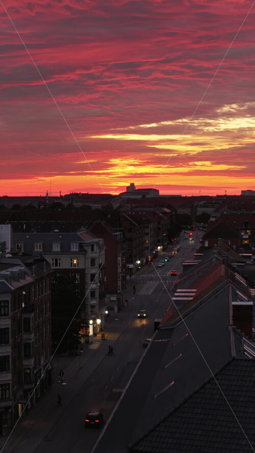 Video - Aerial drone view of of Norrebro rooftops and streets during sunset, with dramatic golden sky over Copenhagen, Denmark. Vertical
