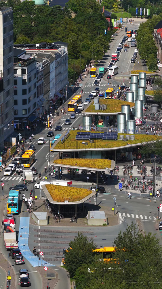 Video - Copenhagen, Denmark - August 6, 2025:Aerial drone view of city traffic, cyclists, and modern green-roofed bike pavilions at Norreport Station. Vertical
