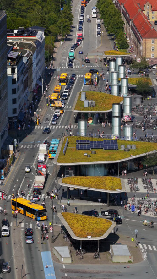Video - Copenhagen, Denmark - August 6, 2025:Aerial drone view of city traffic, cyclists, and modern green-roofed bike pavilions at Norreport Station. Vertical