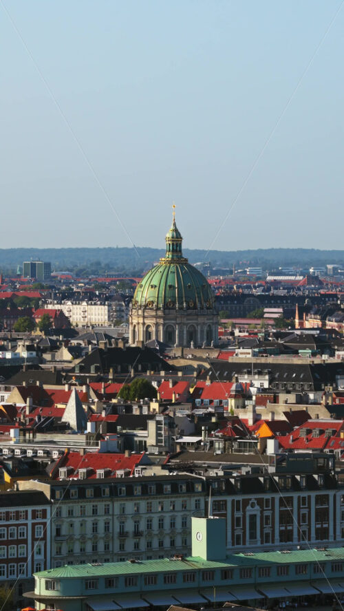 Video - Aerial drone view of the Marble Church in Copenhagen, with its iconic green dome standing out above the city's rooftops on a clear day. Vertical