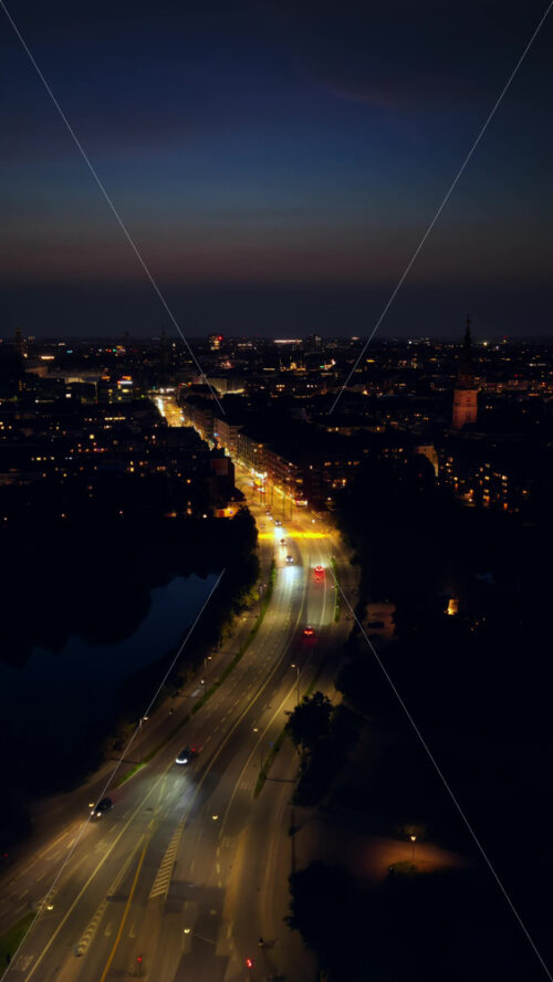 Video - Aerial drone view of Aboulevarden, a major road in Copenhagen, Denmark with streetlights and traffic stretching into the distance at night. Vertical