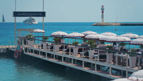 Video - Cannes, France - May 13, 2025: People relaxing under sun umbrellas at a terrace on the beach