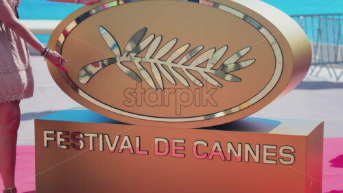 Video - Cannes, France - May 13, 2025: Woman posing with the Cannes Film Festival golden sign