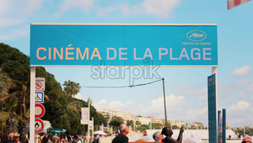 Video - Cannes, France - May 13, 2025: People walking under a beach cinema sign at the Cannes Film Festival