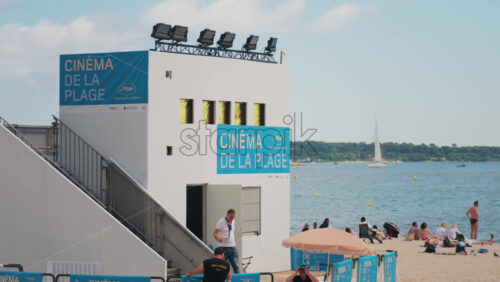 Video - Cannes, France - May 13, 2025: Beach cinema at the Cannes Film Festival with people relaxing on the beach in the background