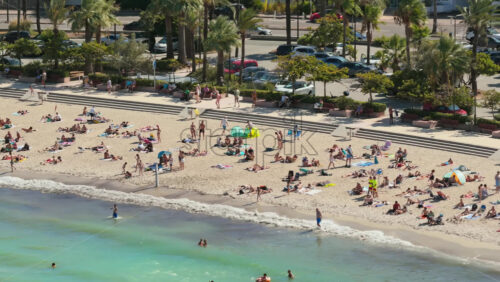 Video - Antibes, France - September 4, 2025: Aerial drone view of sunbathers relaxing on the sandy beach, with people swimming, walking, and enjoying the summer atmosphere along the French Riviera