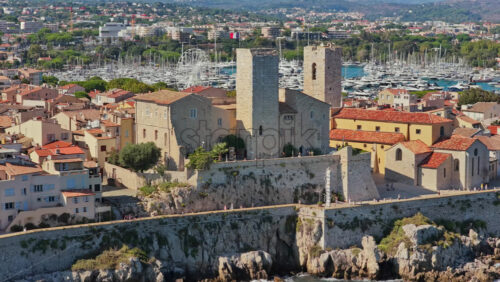 Video - Aerial drone view of the Picasso Museum with its medieval stone towers, overlooking Antibes marina filled with yachts and sailboats