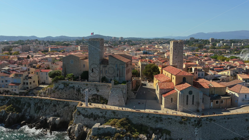 Video - Aerial drone view of the Picasso Museum and medieval stone ramparts overlooking Antibes marina, with yachts docked and the Old Town's terracotta rooftops