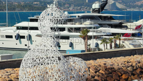 Video - Antibes, France - September 4, 2025: Aerial drone view of the Nomade sculpture by Jaume Plensa in Antibes, with yachts and luxury boats moored in the background