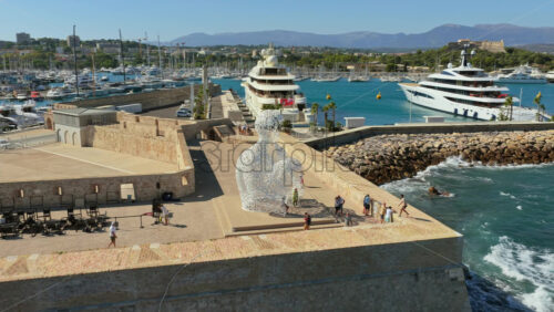Video - Antibes, France - September 4, 2025: Aerial drone view of the Nomade sculpture overlooking Antibes harbor, with superyachts, marina, and coastal scenery in the background