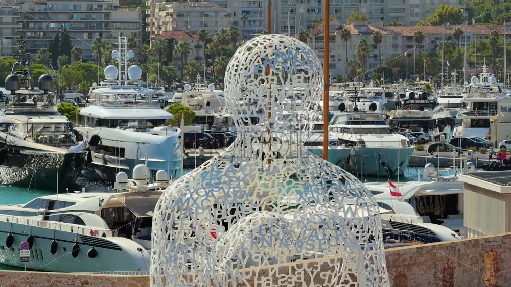 Video - Antibes, France - September 4, 2025: Aerial drone view of the Nomade sculpture by Jaume Plensa in Antibes, with yachts and luxury boats moored in the background