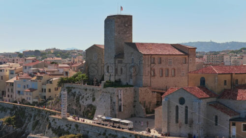 Video - Antibes, France - September 4, 2025: Aerial drone view of the Picasso Museum and medieval ramparts of Antibes, with a tourist train and visitors walking below