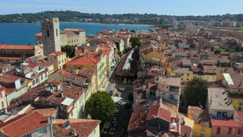 Video - Aerial drone view of Antibes Old Town rooftops with Chateau Grimaldi and church towers facing the Mediterranean Sea