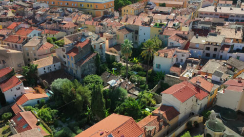 Video - Aerial drone view of Antibes Old Town with palm trees and lush gardens among Mediterranean houses with terracotta rooftops