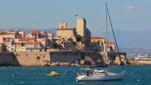 Video - Antibes, France - September 4, 2025: Aerial drone view of a luxury catamaran sailing in front of Antibes Old Town and its medieval stone ramparts