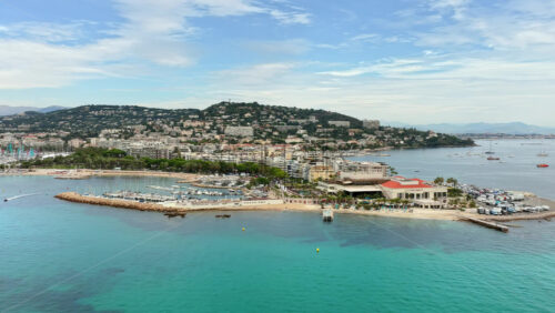Video - Aerial drone view of Cannes coastline with marina, beachfront, and hillside residential buildings