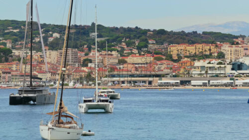 Video - Aerial drone view of luxury yachts anchored offshore with the Palais des Festivals and Cannes city skyline in the background