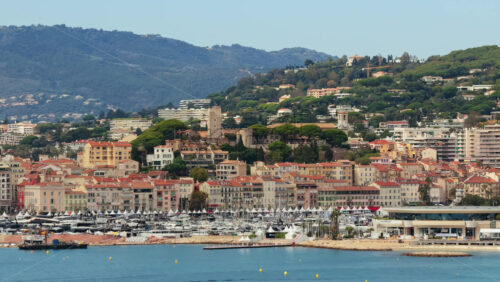 Video - Aerial drone view of Cannes Old Town Le Suquet with historic tower, colorful rooftops, and luxury yachts in the marina