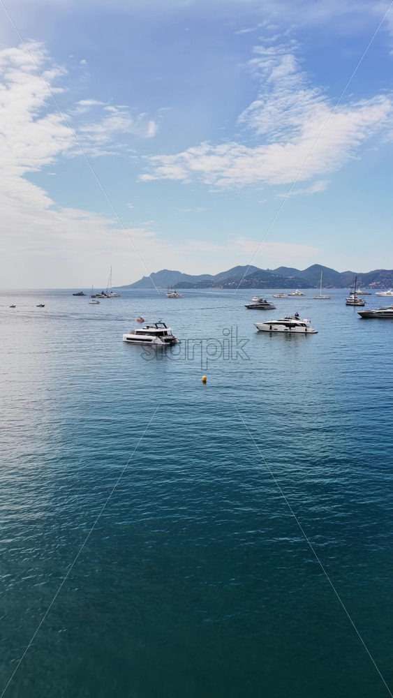 Video - Aerial drone view of dozens of yachts and sailboats anchored in the calm turquoise waters off Cannes. Vertical