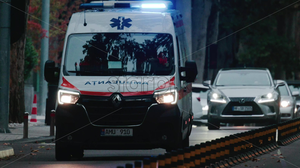 Video - Chisinau, Moldova - October 1, 2025: Emergency ambulance driving through a city street with flashing blue lights during dusk