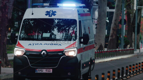 Video - Chisinau, Moldova - October 1, 2025: Emergency ambulance driving through a city street with flashing blue lights during dusk
