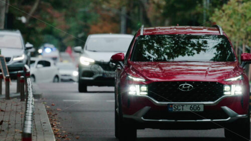 Video - Chisinau, Moldova - October 1, 2025: Vehicles driving along a wet city street at dusk with headlights on