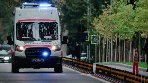 Video - Chisinau, Moldova - October 1, 2025: Emergency ambulance driving through a city street with flashing blue lights during dusk