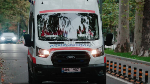 Video - Chisinau, Moldova - October 1, 2025: Emergency ambulance driving through a city street with flashing blue lights during dusk