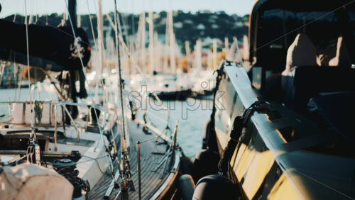 Video - Close view of yachts and sailboats docked side by side in a scenic marina during golden hour