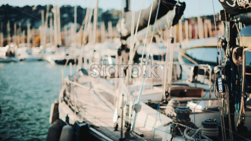 Video - Close view of yachts and sailboats docked side by side in a scenic marina during golden hour